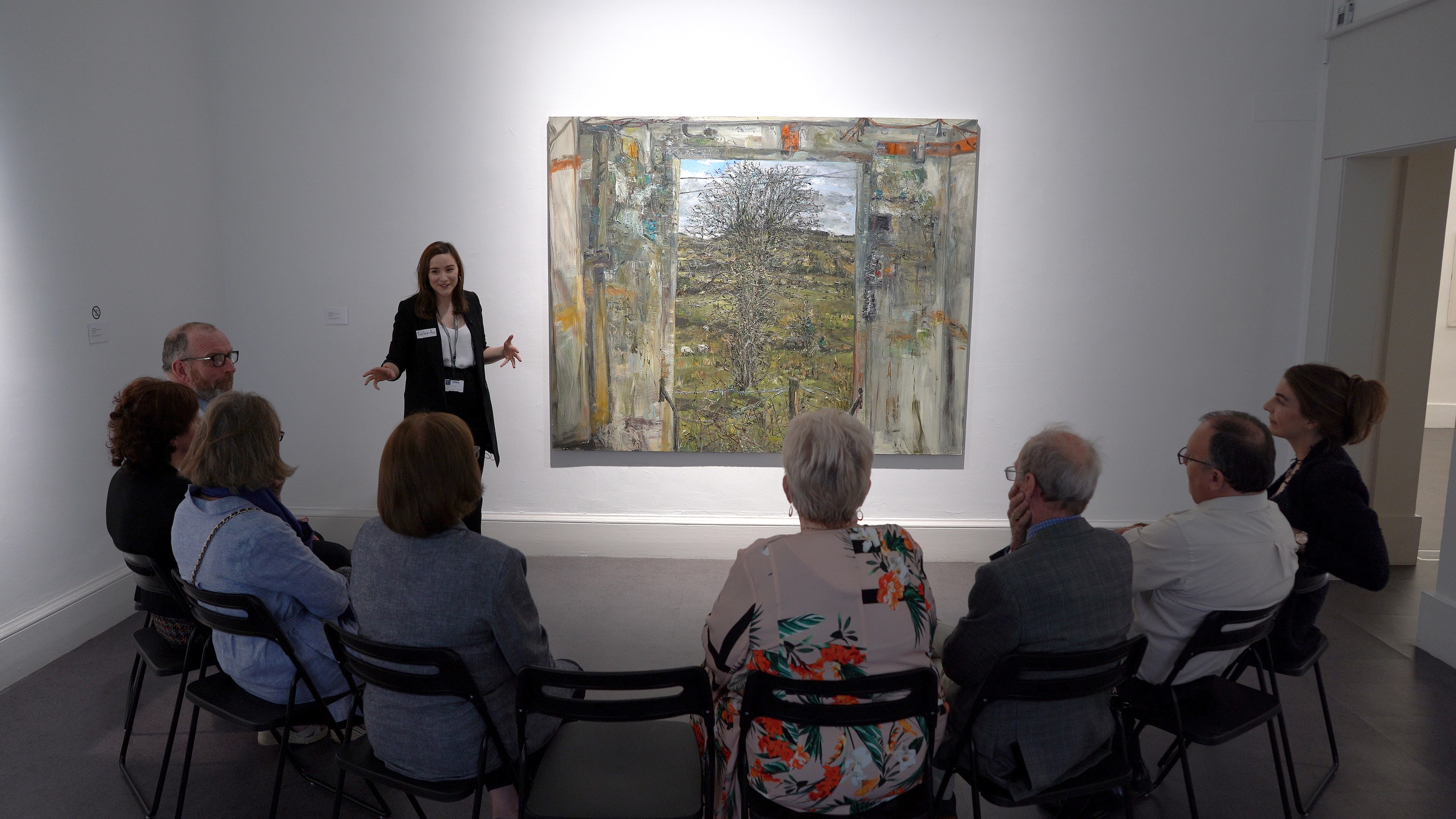 Curator and group of people in front of an exhibit