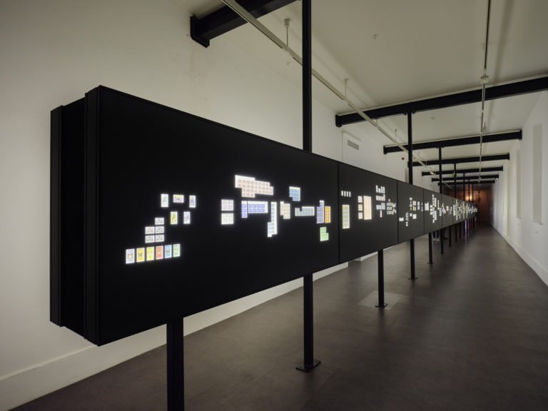 Gallery thumbnail. Statecraft: An Incomplete Timeline of Independence Determined by Digital Auction, 2014–2019, Lightboxes, postage stamps, LED lights. Installation view The Otolith Group: Xenogenesis, IMMA. 2022.  Image courtesy of the artists and IMMA, Dublin. Photo: Ros Kavanagh