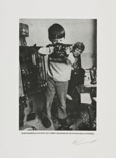 Sean Shannon plays with toy tommy gun made by his father while interned